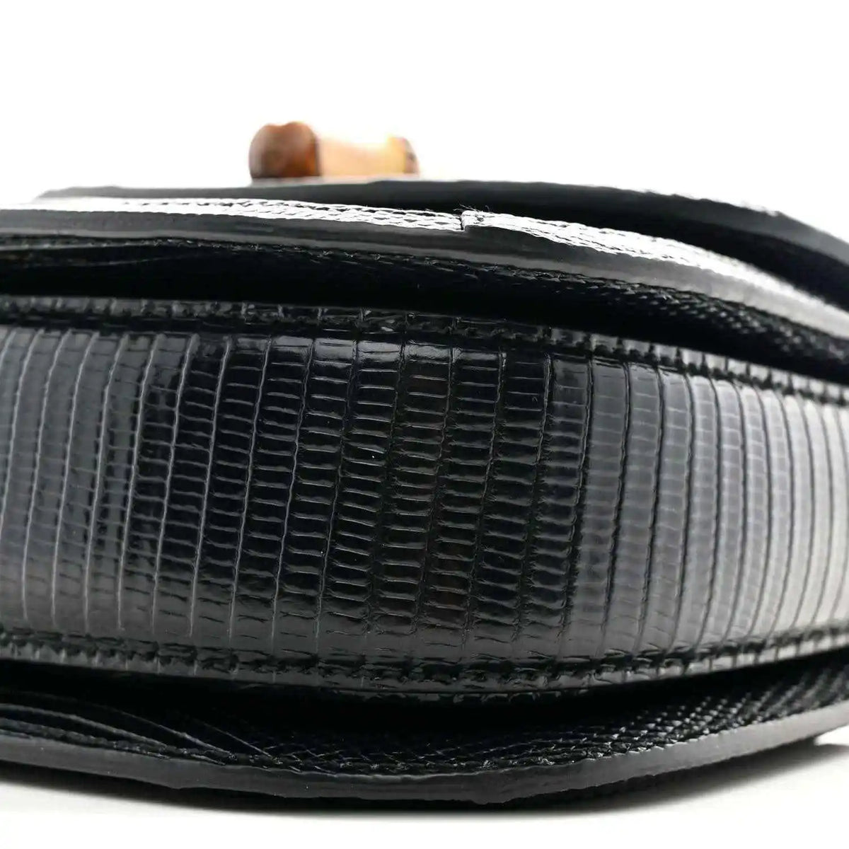 Close-up of black mini bag side with embossed grid texture and contrasting trim