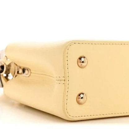 Cream mini handbag end with metal studs and side seam stitching detail.