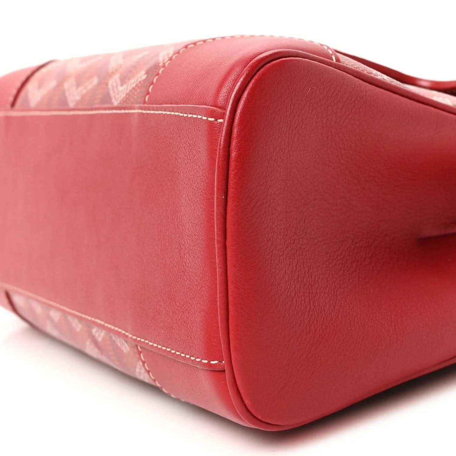 Red mini handbag corner with rounded leather edge and coated canvas panel.