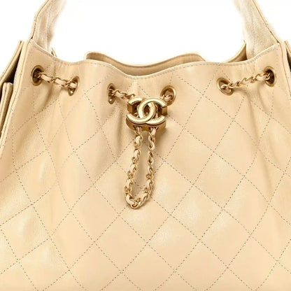 Light beige quilted handbag top with gold CC charm and chain pull tab