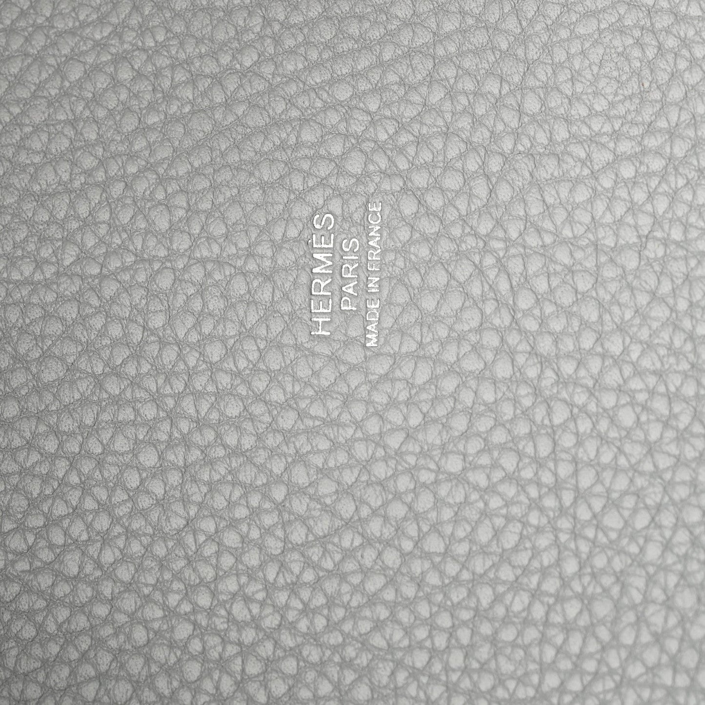 Close-up of light blue pebbled leather with embossed stamp and text