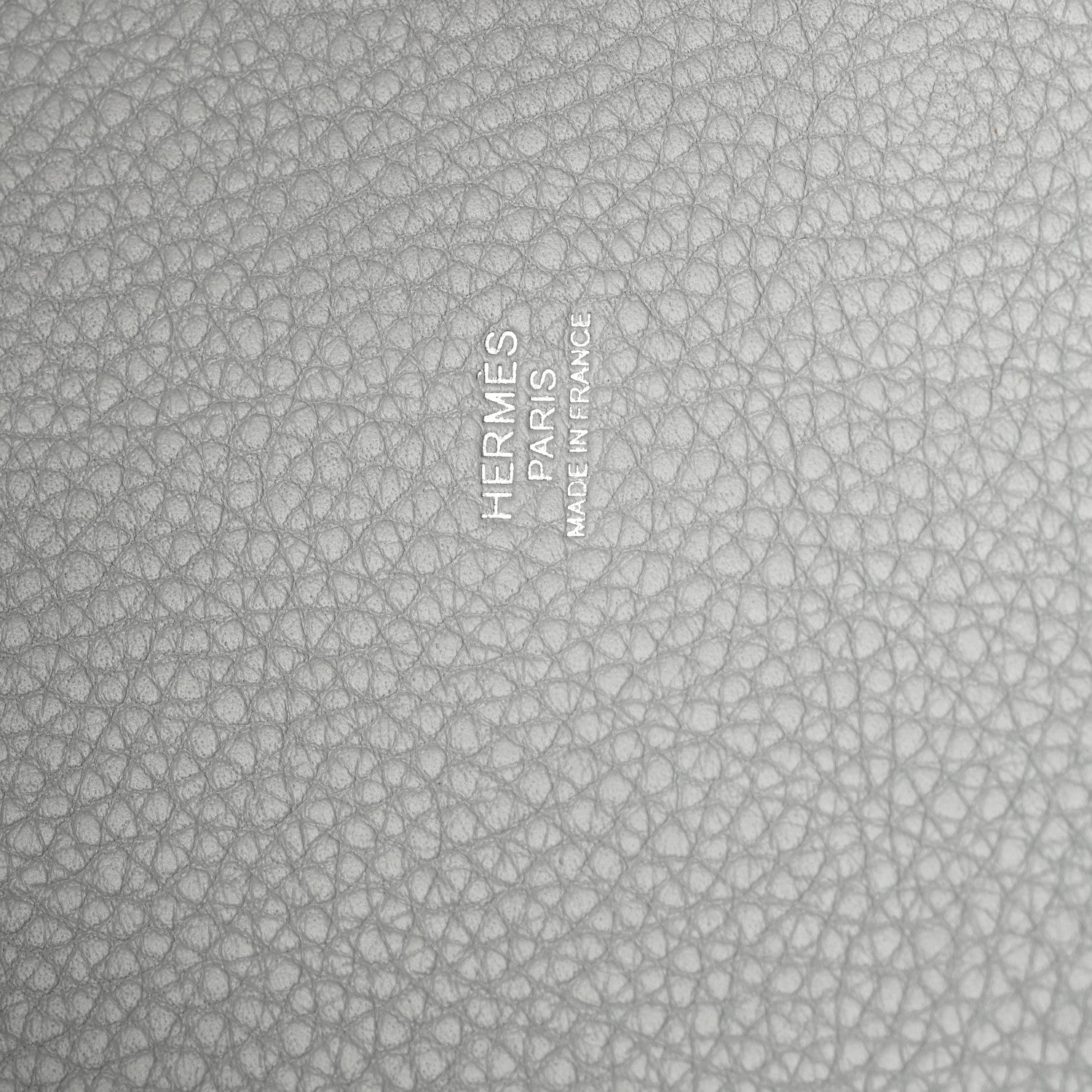 Close-up of light blue pebbled leather with embossed stamp and text