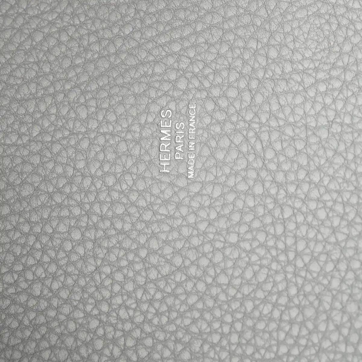 Close-up of light blue pebbled leather with embossed stamp and text