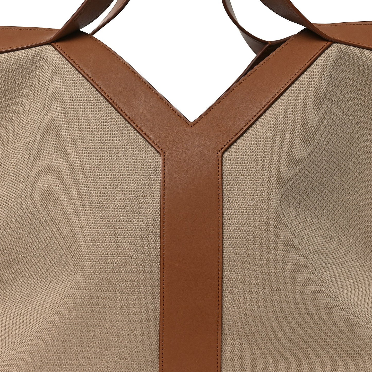 Beige canvas tote bag with brown leather Y-shaped front panels and top handles