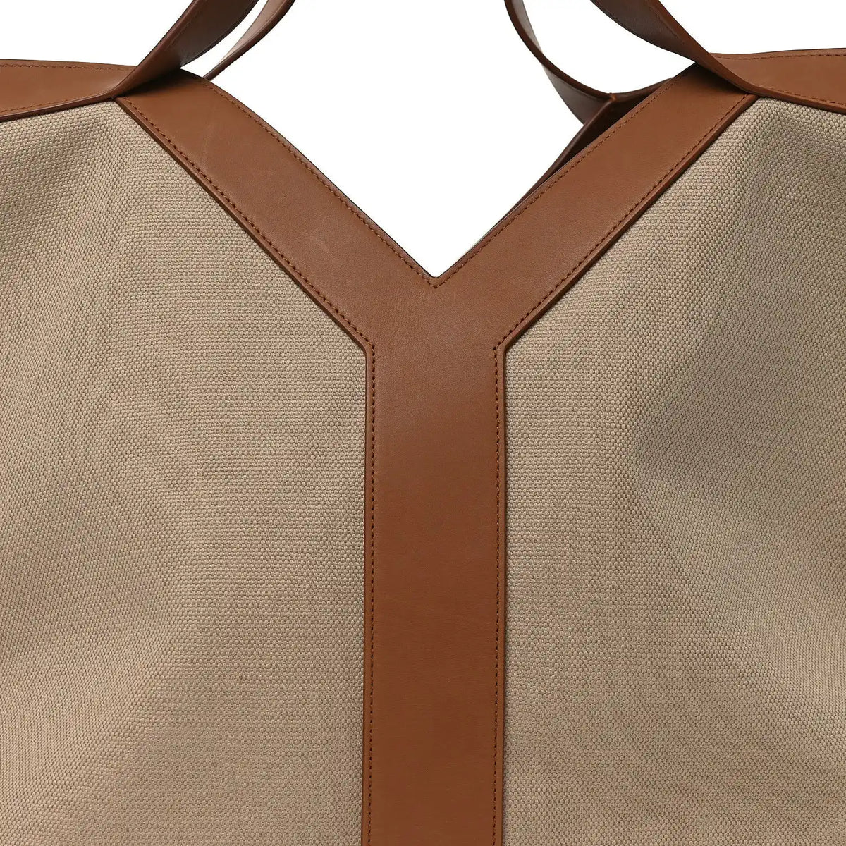 Beige canvas tote bag with brown leather Y-shaped front panels and top handles