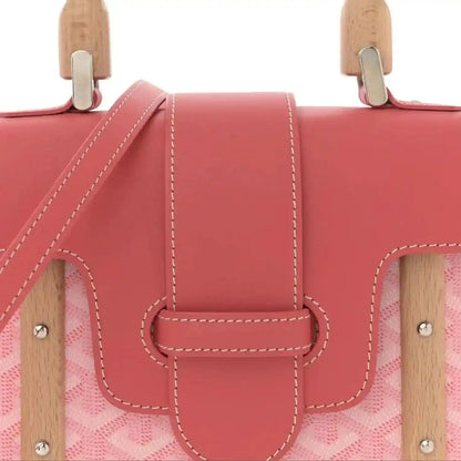 Pink bag front with wooden top handles and central leather clasp with double stitching.