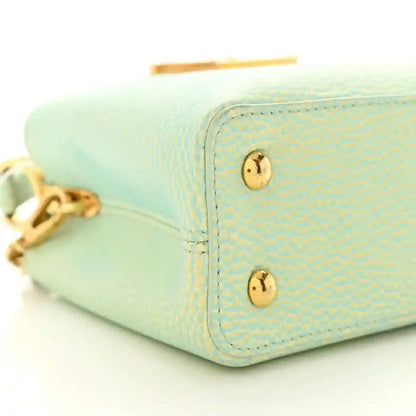 Mini Capucines handbag in light green textured leather with gold corner studs