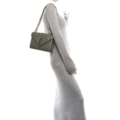 Light sage quilted satchel on shoulder with chain strap and flap closure
