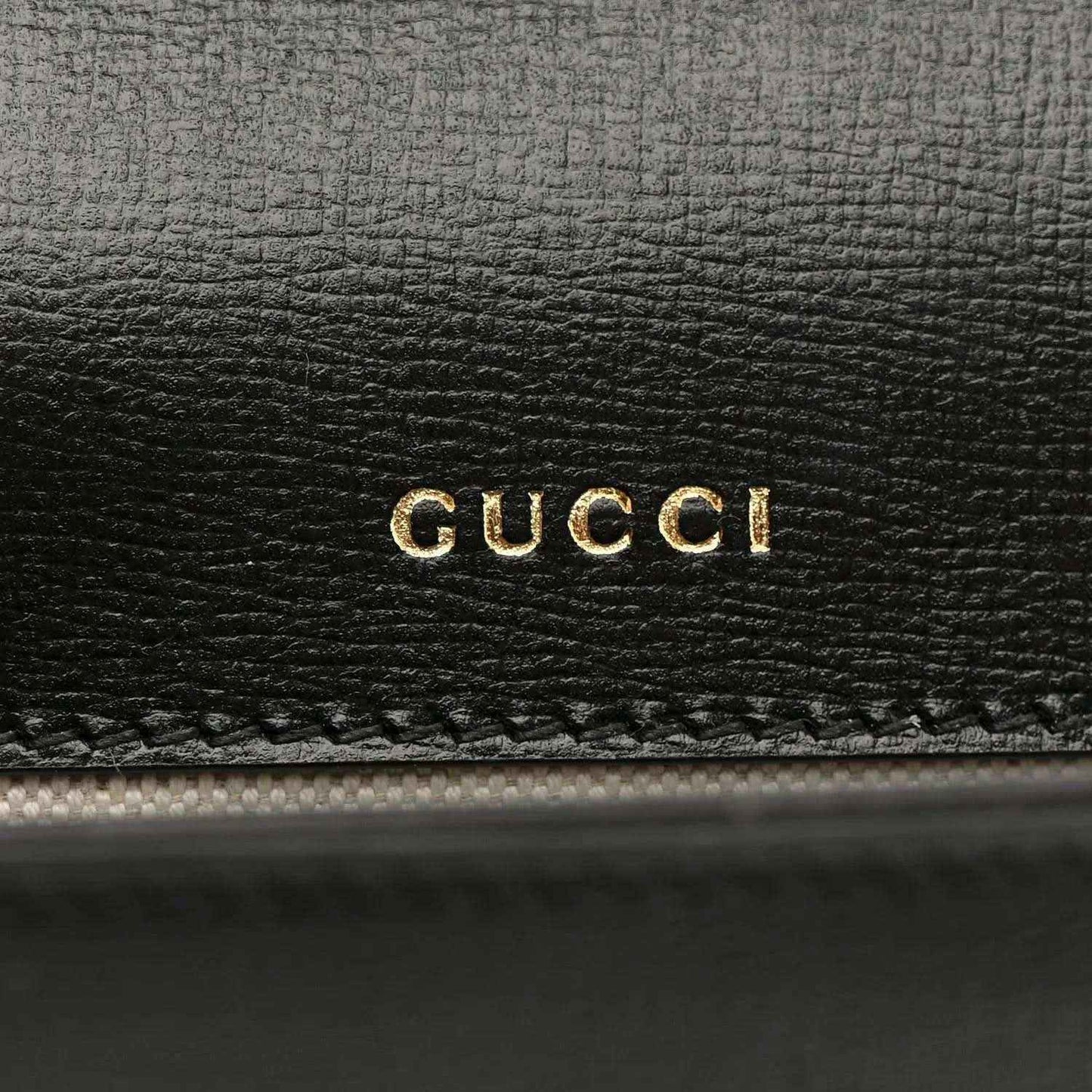 Black leather mini bag with gold GUCCI logo embossing on front panel