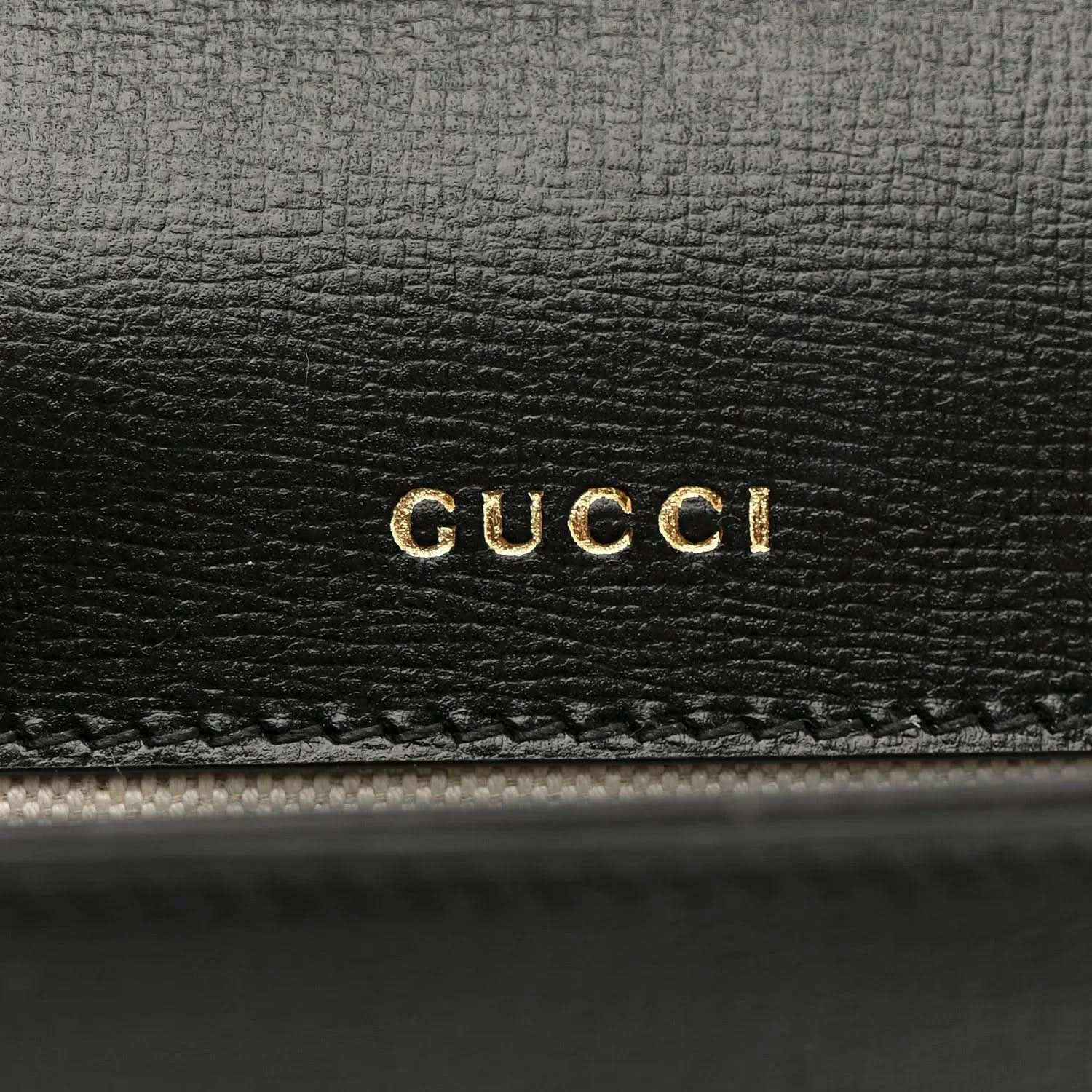 Black leather mini bag with gold GUCCI logo embossing on front panel