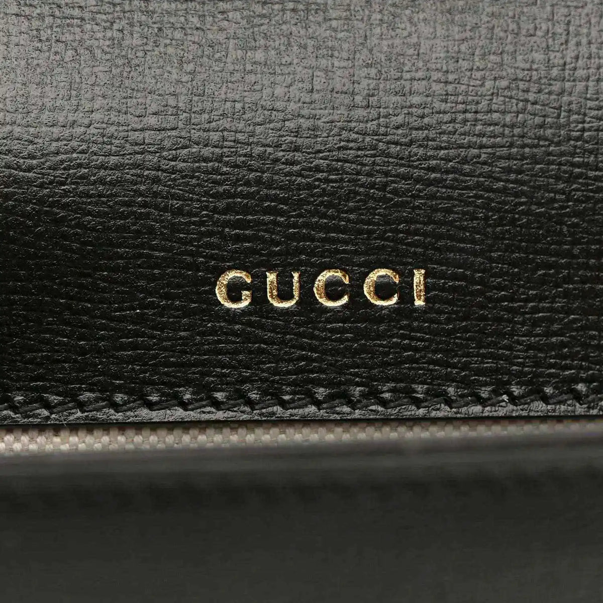 Black leather mini bag with gold GUCCI logo embossing on front panel