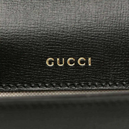 Black leather mini bag with gold GUCCI logo embossing on front panel