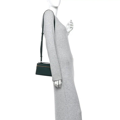 Dark green leather crossbody pouch with adjustable strap, worn at the side.