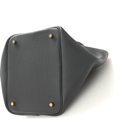 Dark gray leather handbag with corner studs and textured grain on angled side