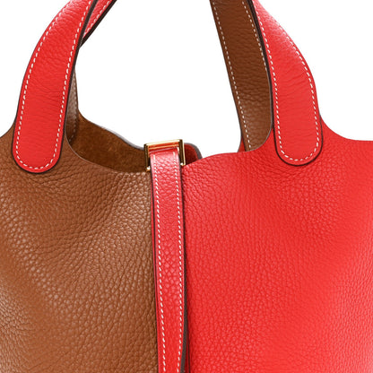 Two-tone leather tote with top handles and gold-tone center clasp, red and brown
