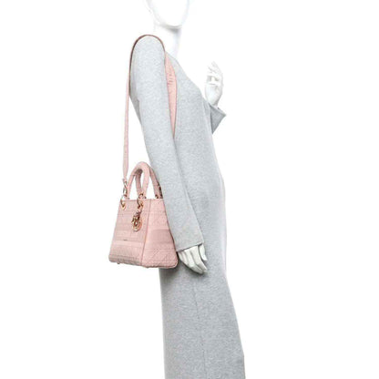 Pink canvas bag with long shoulder strap and gold-tone clasp hardware