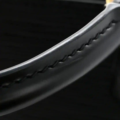Black leather handbag detail with braided trim and stitched edge