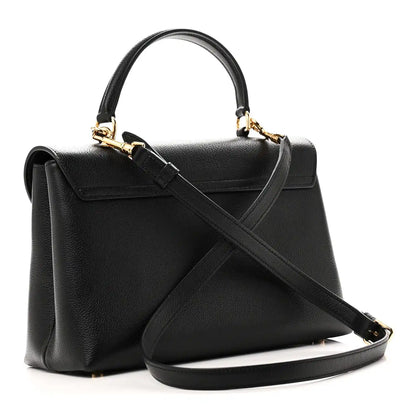 Black leather top-handle handbag with diagonal shoulder strap and gold-trim front flap