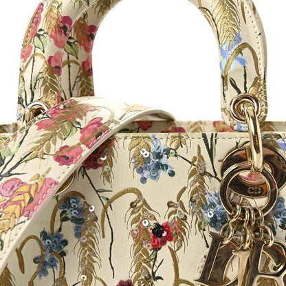 Floral embroidered top handles with gold-tone ring hardware on a cream tote