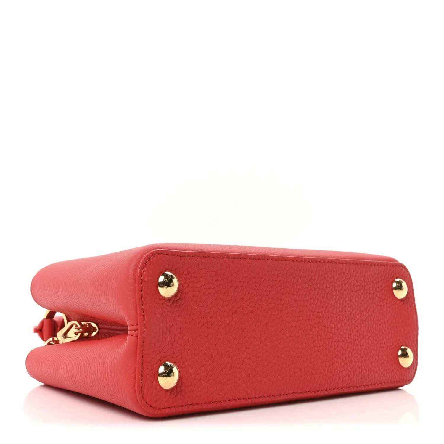Red leather mini handbag bottom view with two gold stud feet and chain hardware.