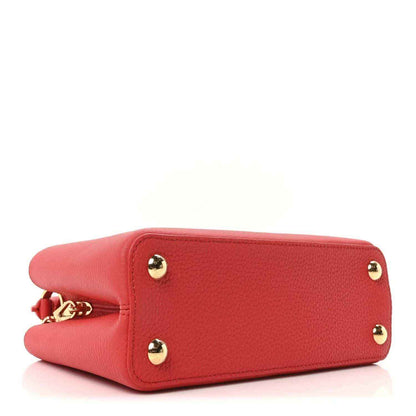 Red leather mini handbag bottom view with two gold stud feet and chain hardware.