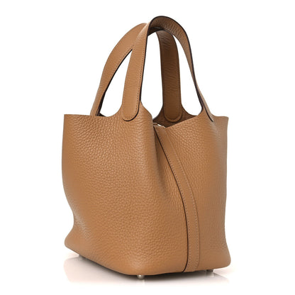 Tan textured leather tote bag with top handles and front lock clasp, side view.