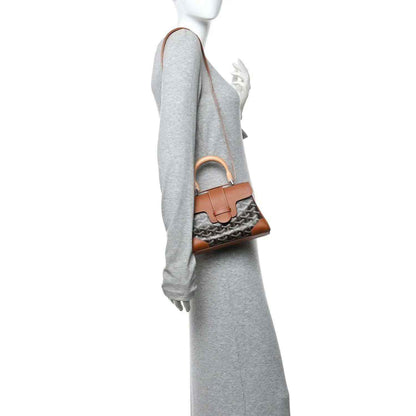 Mini shoulder bag worn on shoulder, tan leather trim with dark patterned canvas body
