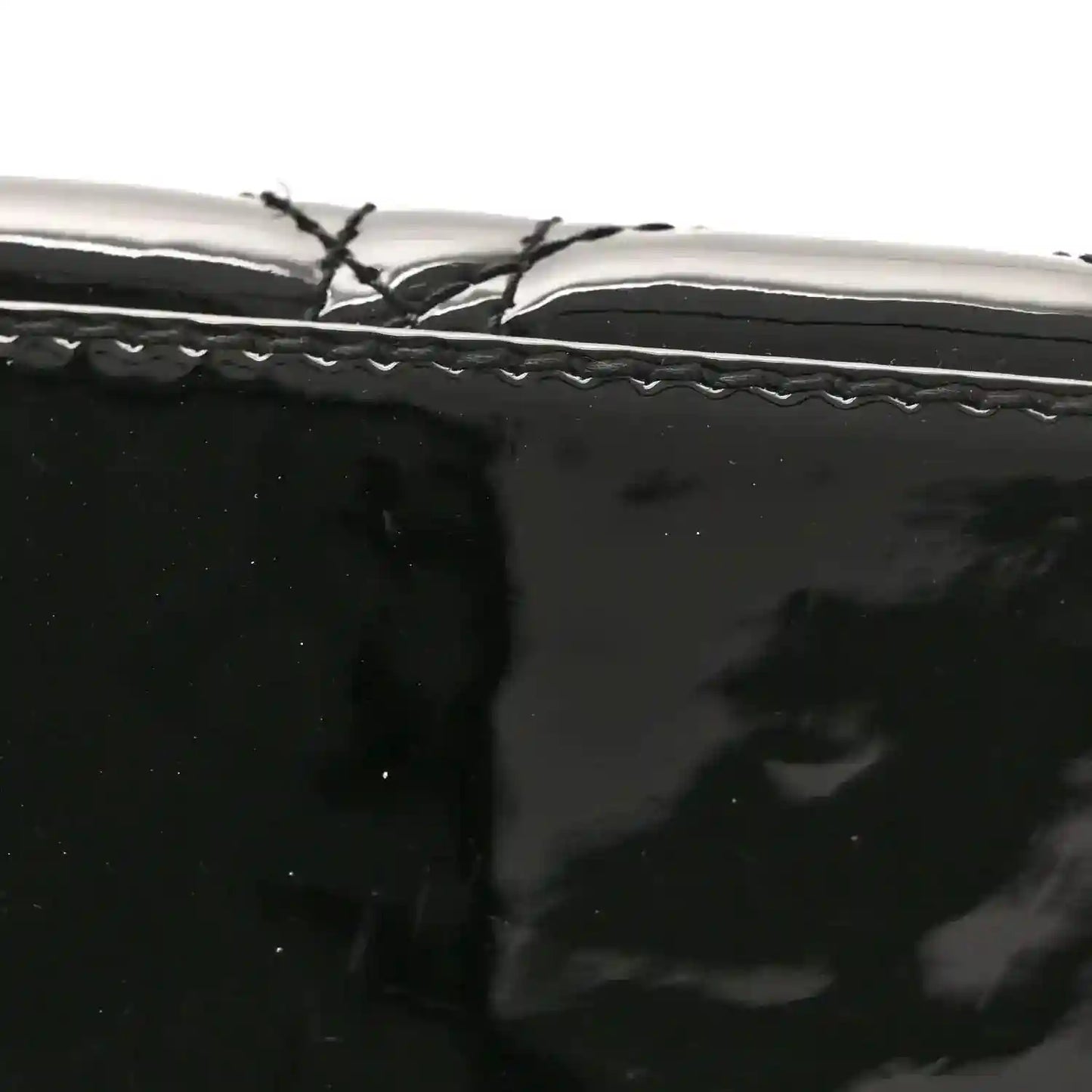 Black patent handbag with stitched trim and smooth surface
