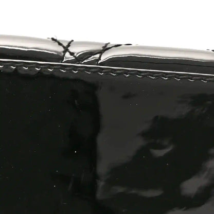 Black patent handbag with stitched trim and smooth surface