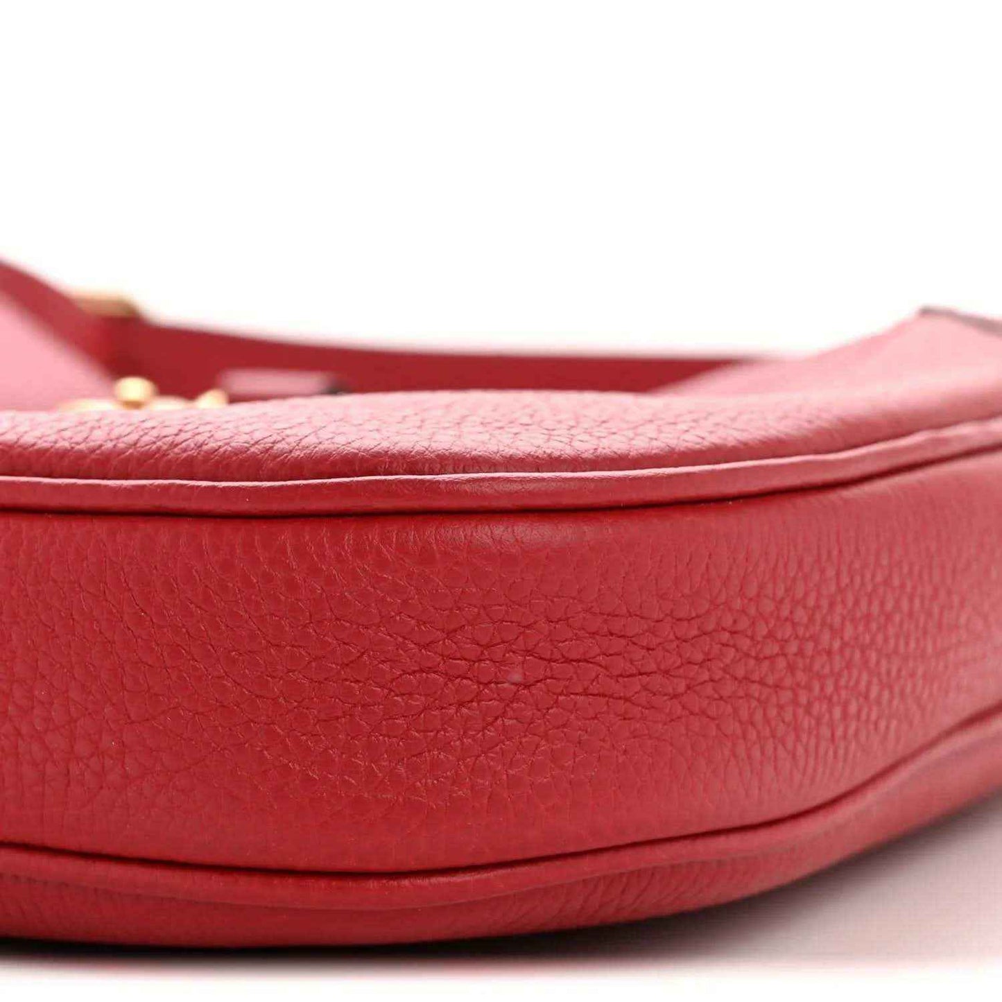 Red leather hobo bag close-up of curved base and pebbled texture