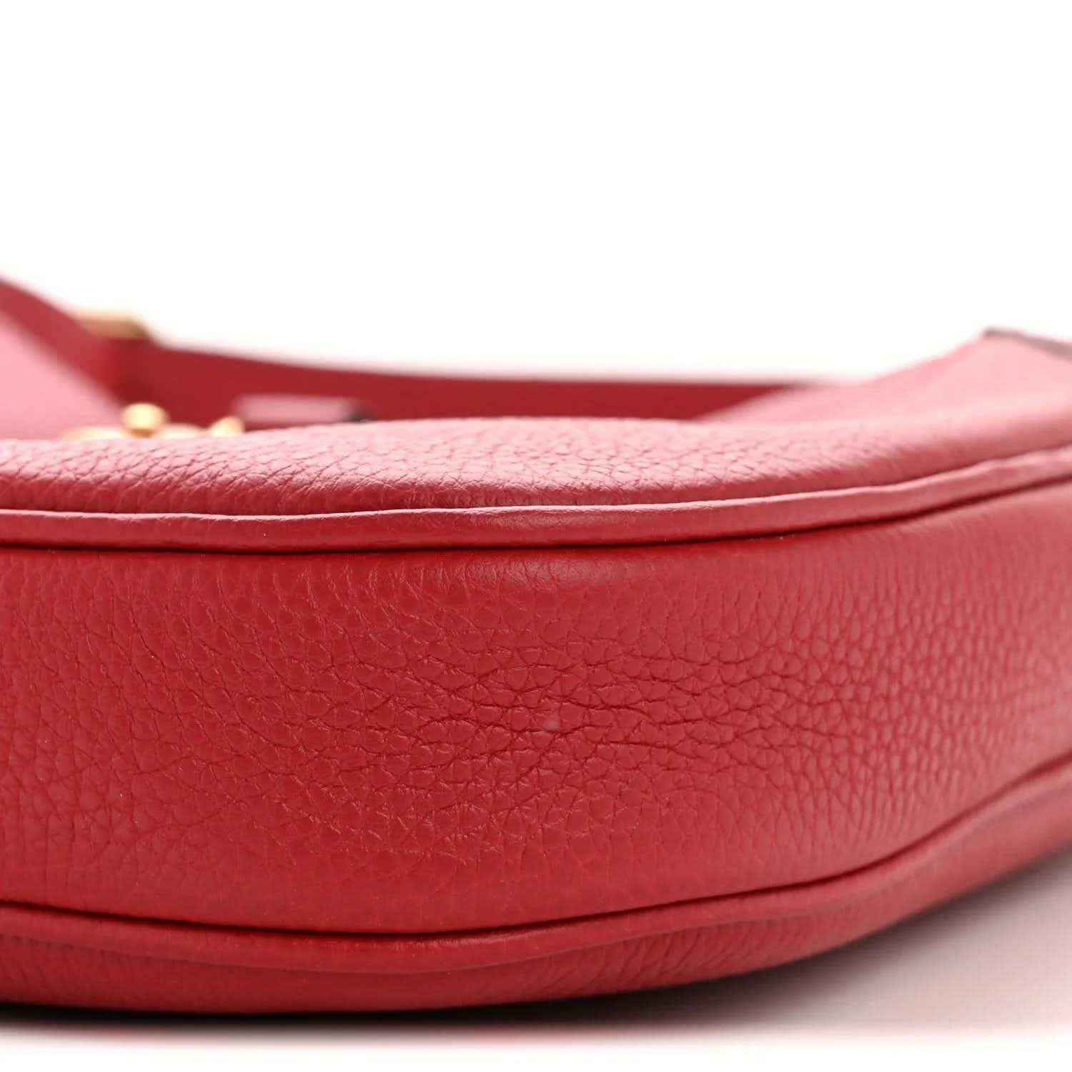 Red leather hobo bag close-up of curved base and pebbled texture