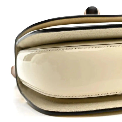 White mini handbag with glossy front panel and stitched flap edge