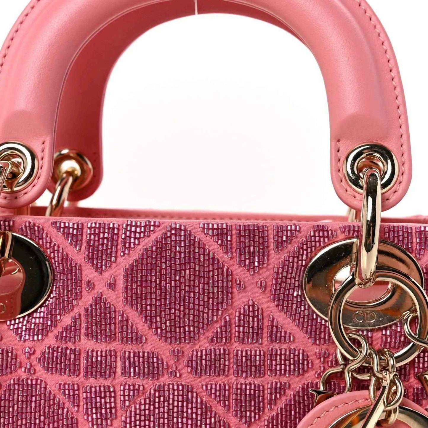 Mini Lady Dior handbag closeup of light pink top handles and beaded lattice charm hardware