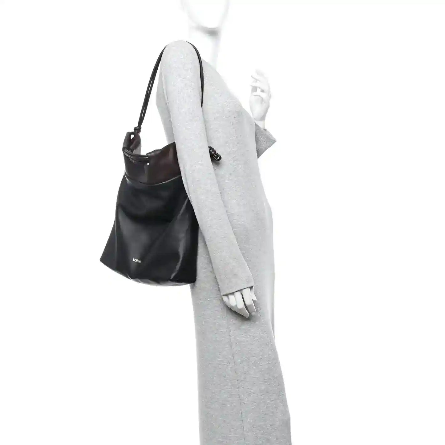 Black leather tote bag worn over a long-sleeve outfit with crossbody strap.