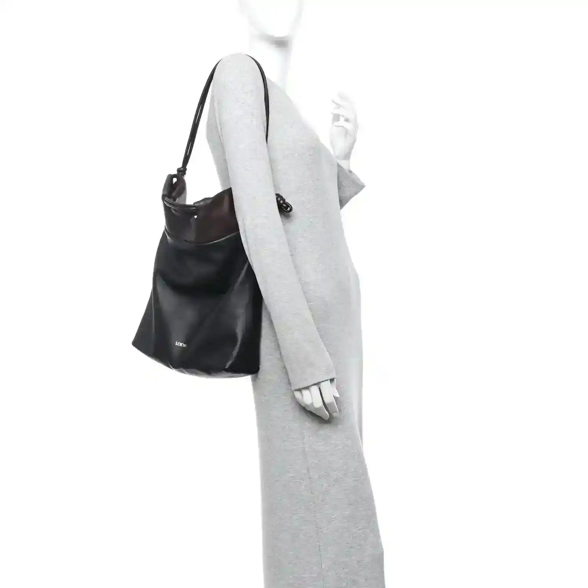 Black leather tote bag worn over a long-sleeve outfit with crossbody strap.