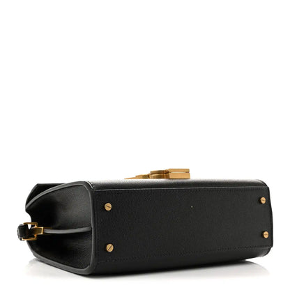 Black leather mini top-handle bag with gold studs and flap opening.