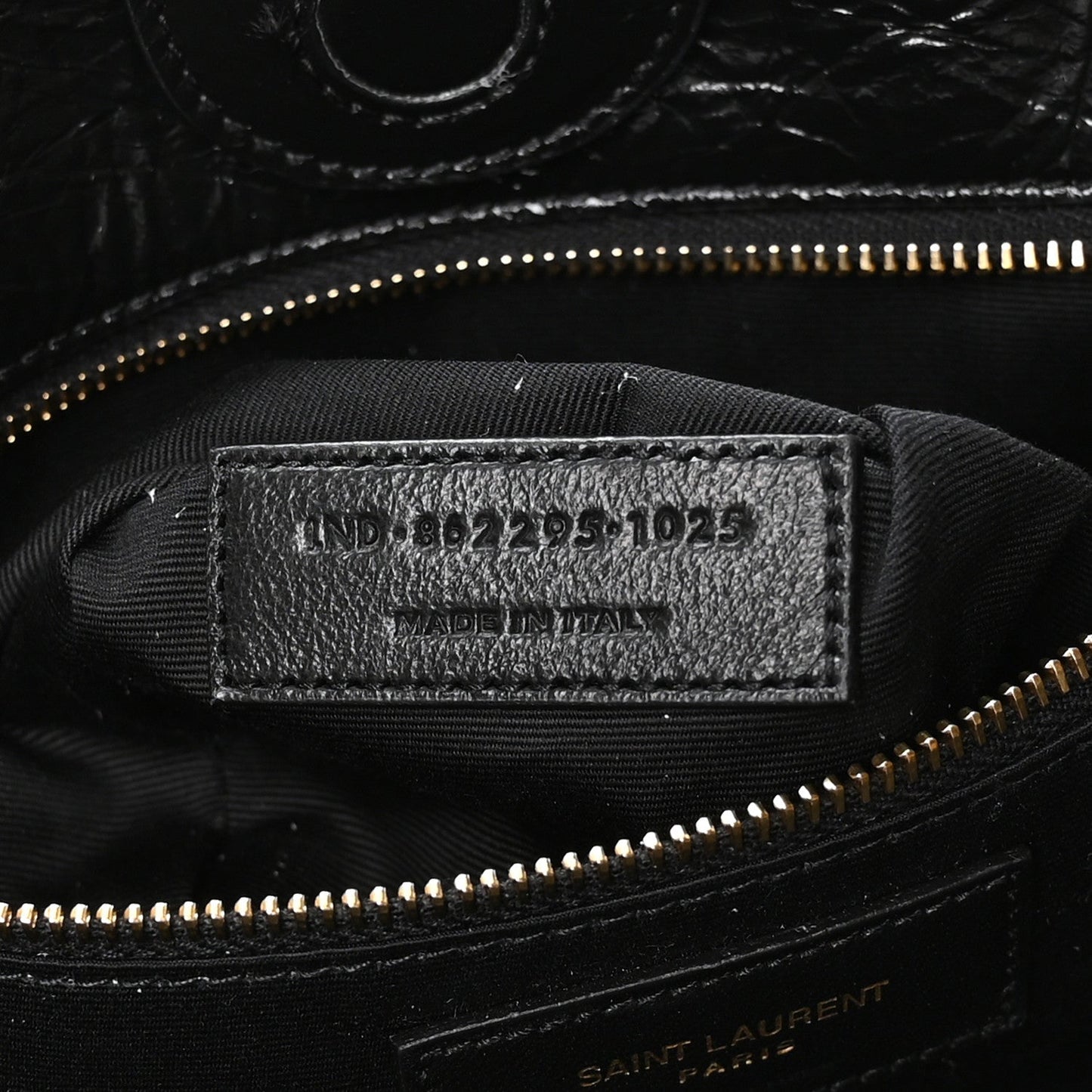 Black interior label with style code and gold zipper near top seam