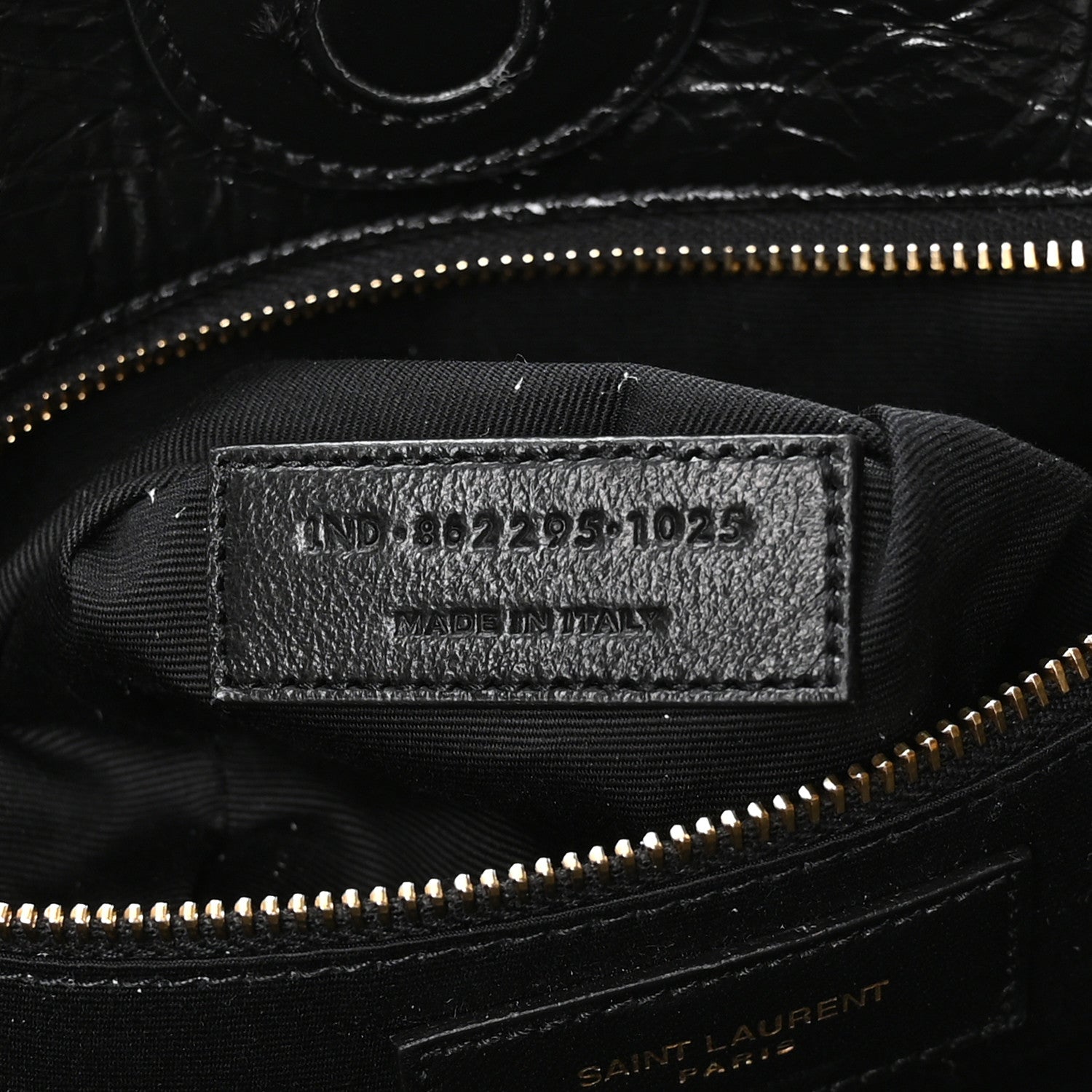 Black interior label with style code and gold zipper near top seam