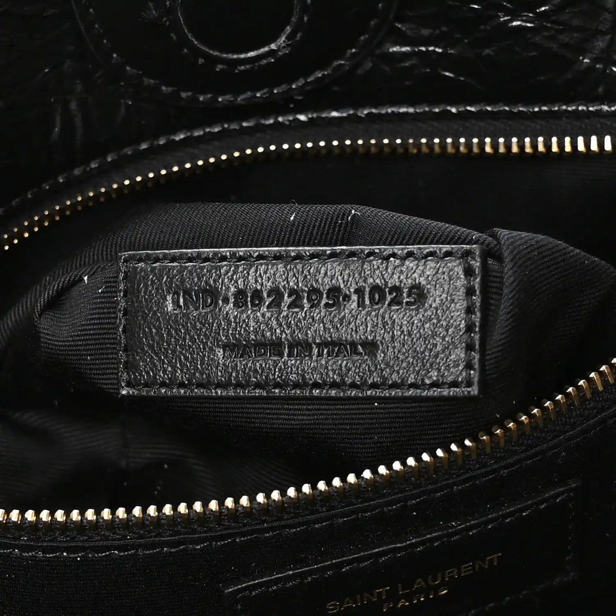 Black interior label with style code and gold zipper near top seam