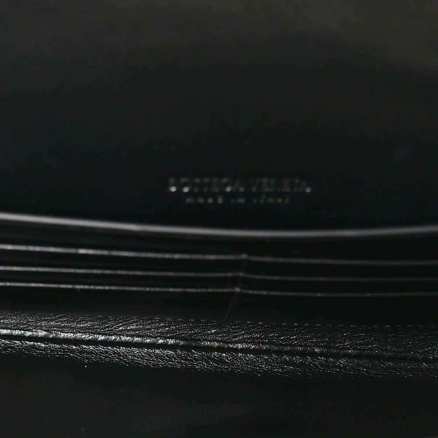 Black leather clutch flap detail with subtle stitching and hardware