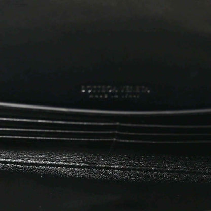 Black leather clutch flap detail with subtle stitching and hardware