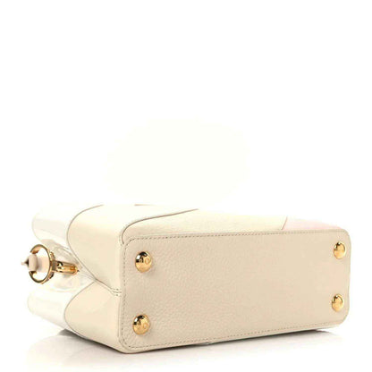 Cream leather handbag with top handle strap, gold-tone studs, and side pocket