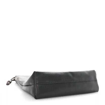 Black leather tote bag shown from the side with a flat folded top edge.