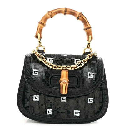 Black mini shoulder bag with bamboo top handle, gold chain strap, and embossed logo pattern