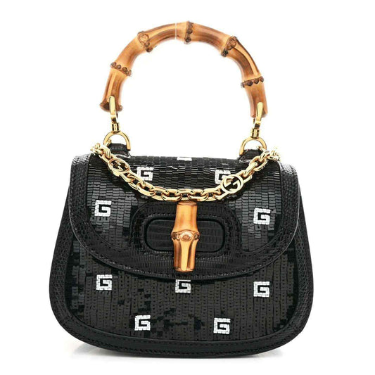 Black mini shoulder bag with bamboo top handle, gold chain strap, and embossed logo pattern
