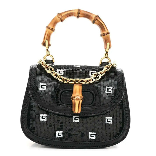 Black mini shoulder bag with bamboo top handle, gold chain strap, and embossed logo pattern