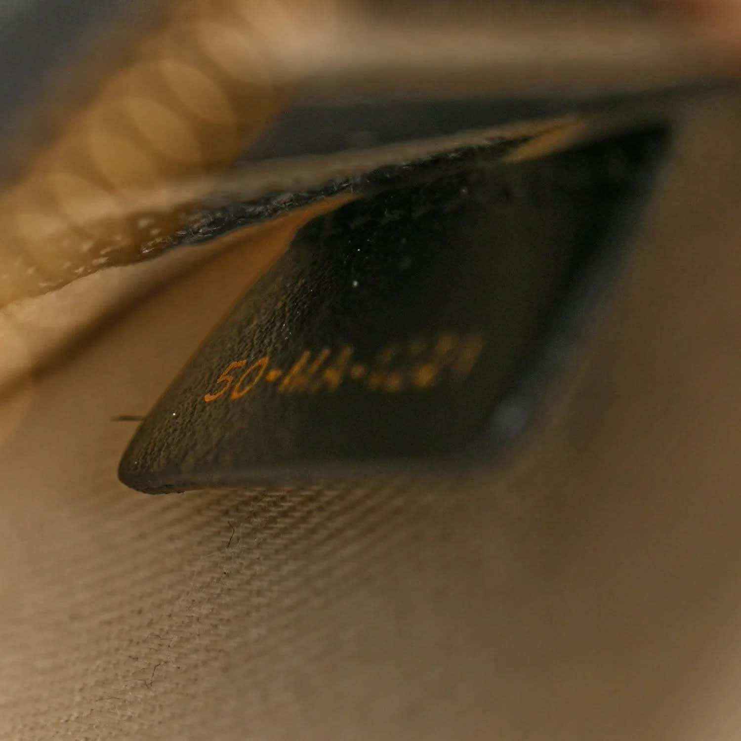 Leather strap end with gold Christian Dior Paris lettering and stitching detail.