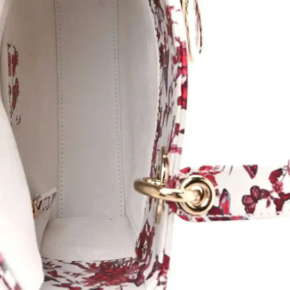 White leather-lined interior of floral handbag with gold-tone snap clasp