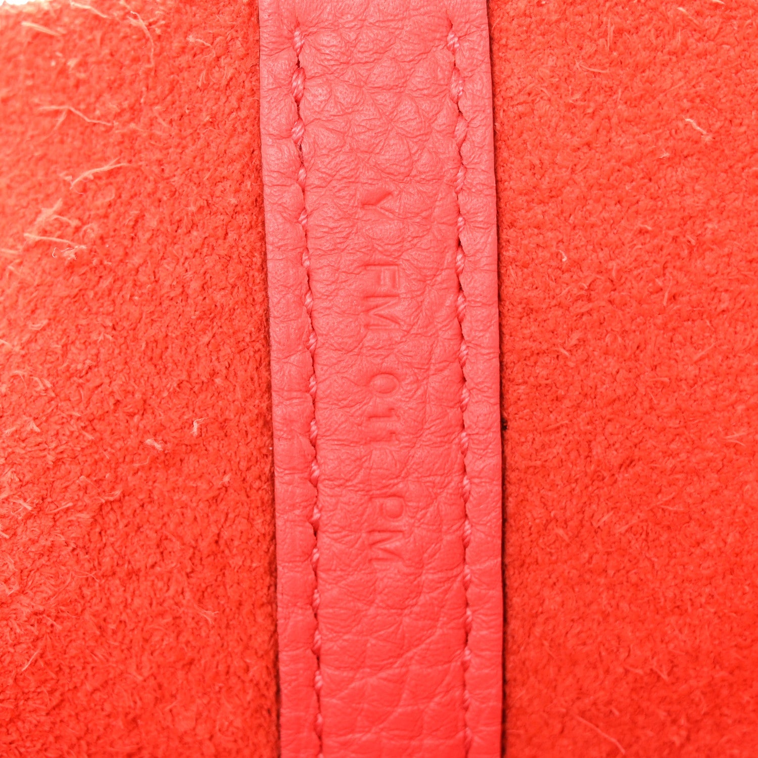 Rose pink leather strap section with embossed text and stitching detail