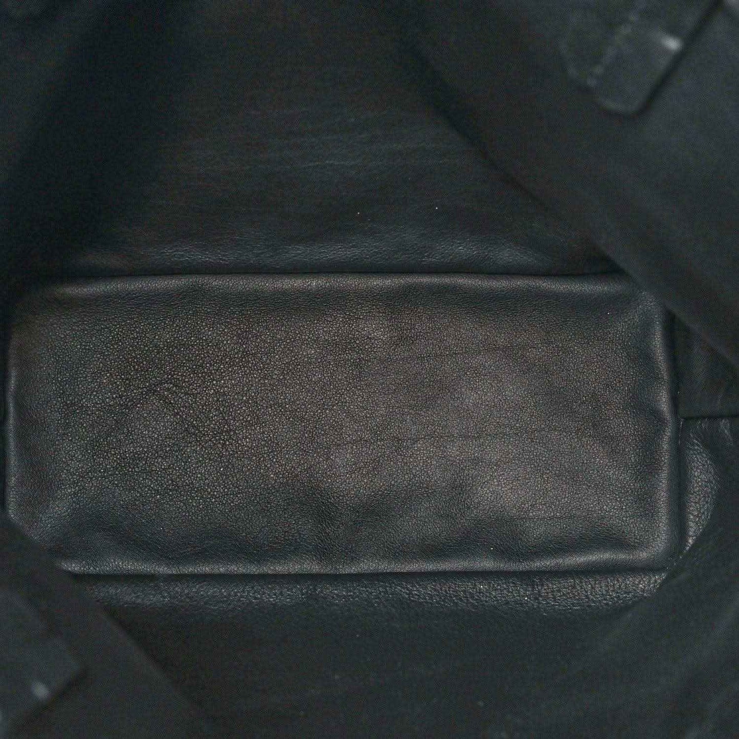 Black leather-like interior pocket panel of a reversible mini tote bag with seams.